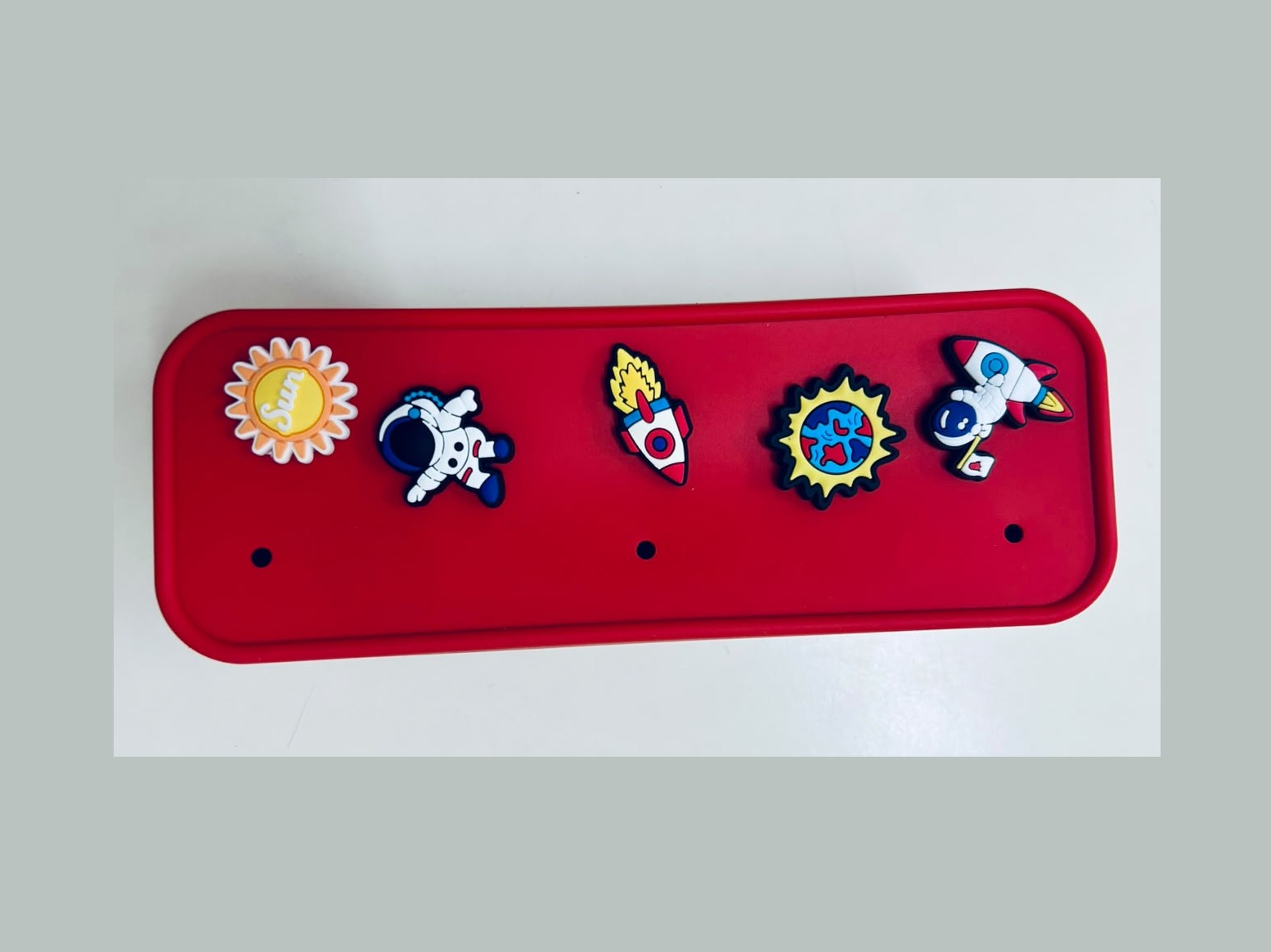 Trousse Dodoupi rouge décorée de charms sur le thème de l'espace : fusée, planète, astronaute et soleil